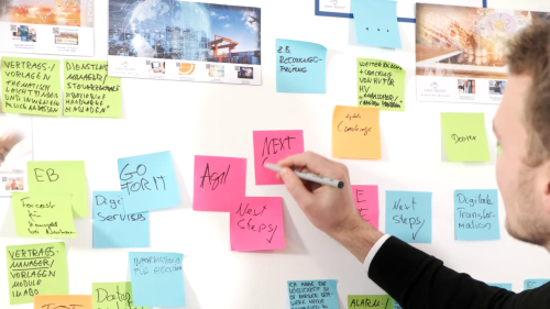 Young man agilely generating ideas with post-its on a wall